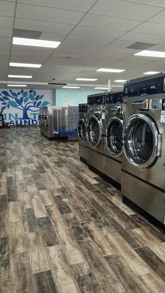 Wood-look porcelain tile installed throughout a commercial laundry — slip-resistant and built for heavy foot traffic and water exposure.