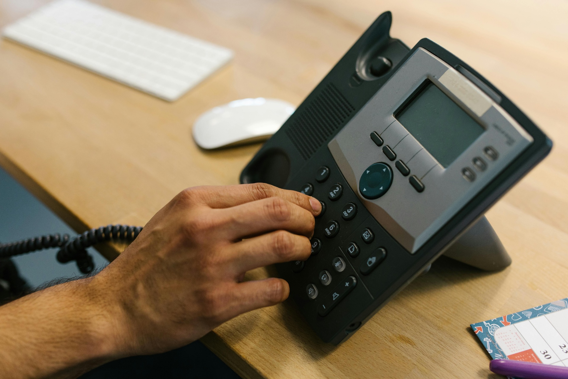 Hand dialing a desk phone in an office