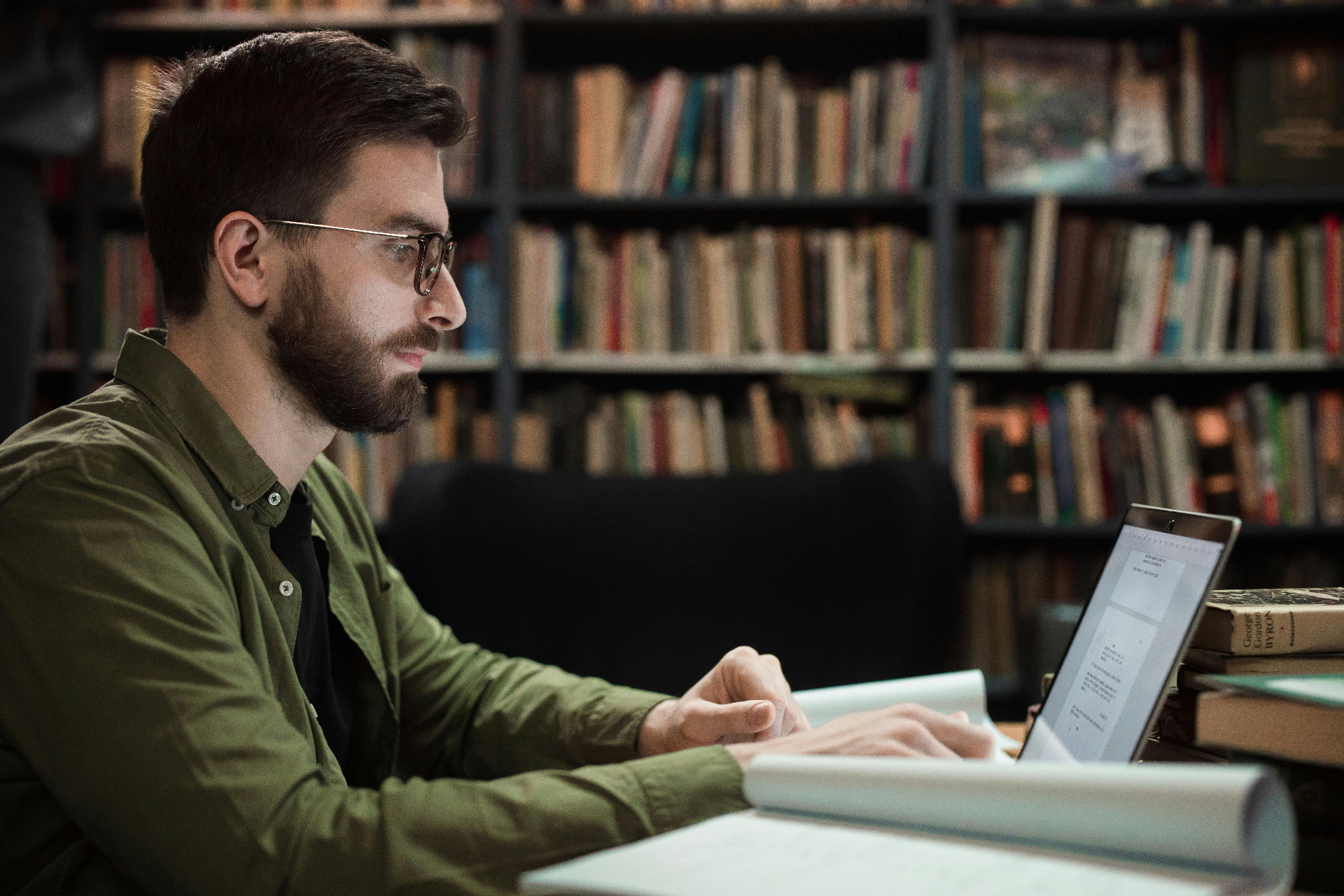 Person reading and writing at a desk in a library