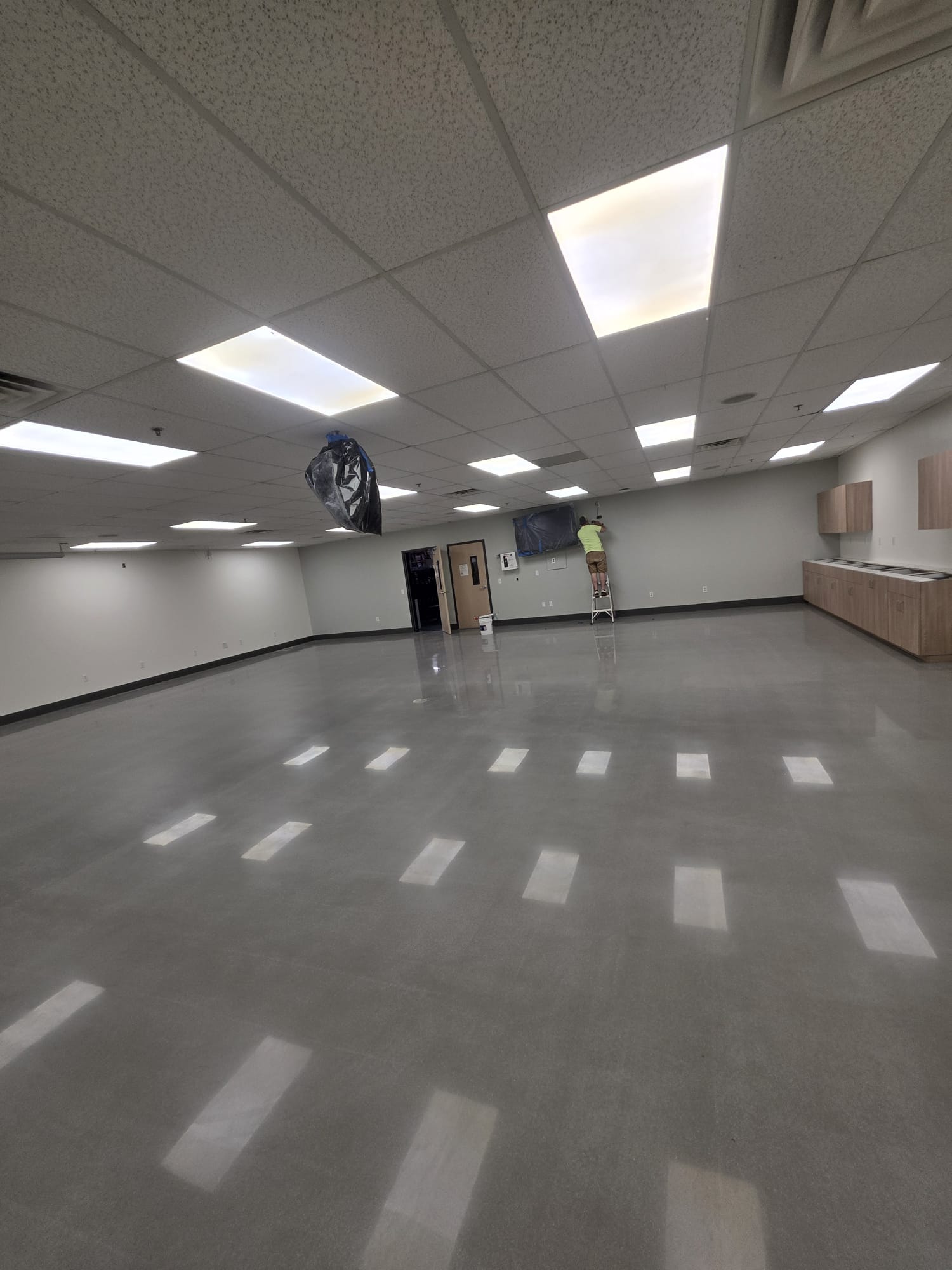 Wide view of the finished breakroom with new cabinetry — uniform sheen across the full slab.