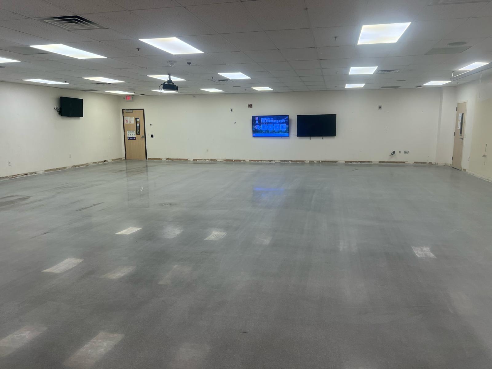 Training room slab before polishing — old flooring stripped, adhesive residue exposed, ready for grind.