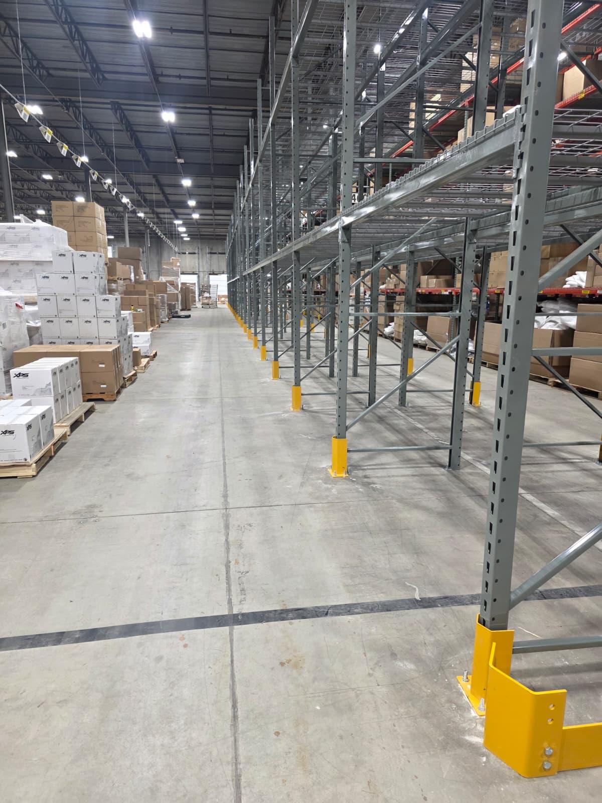 Yellow column protectors installed at every upright to absorb forklift impacts.