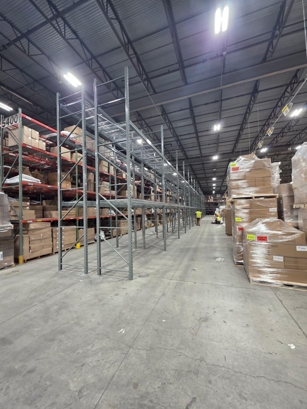 New pallet rack bays set, plumbed, and anchored alongside an active pick aisle.